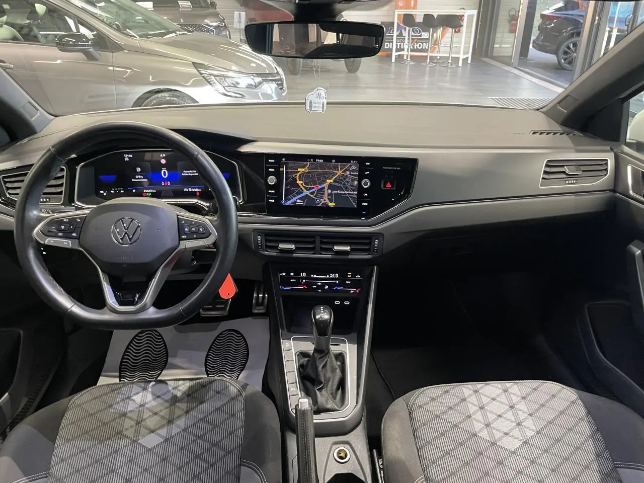 Vue intérieure avant de la Volkswagen Polo 2024 R-Line avec tableau de bord numérique et sellerie tissu gris à motifs.