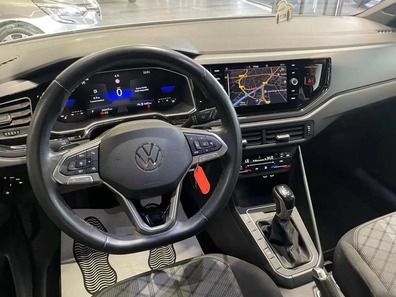 Vue intérieure avant du tableau de bord et volant cuir multifonction d'une Volkswagen Polo 2024 blanche, avec écran tactile et levier de boîte auto.