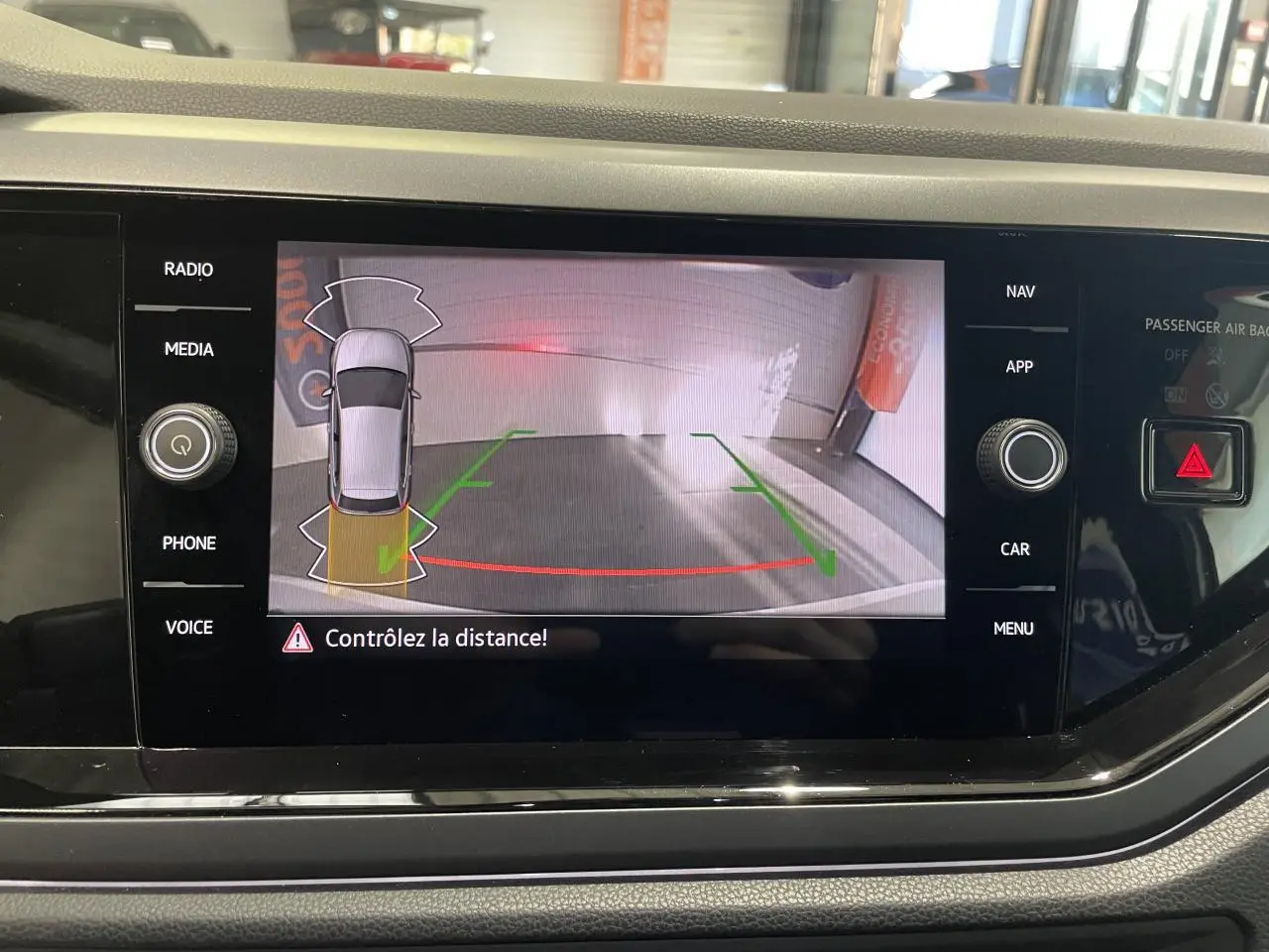 Écran tactile intérieur montrant la caméra de recul d'une Volkswagen Polo blanche, vue arrière avec guidage de stationnement.