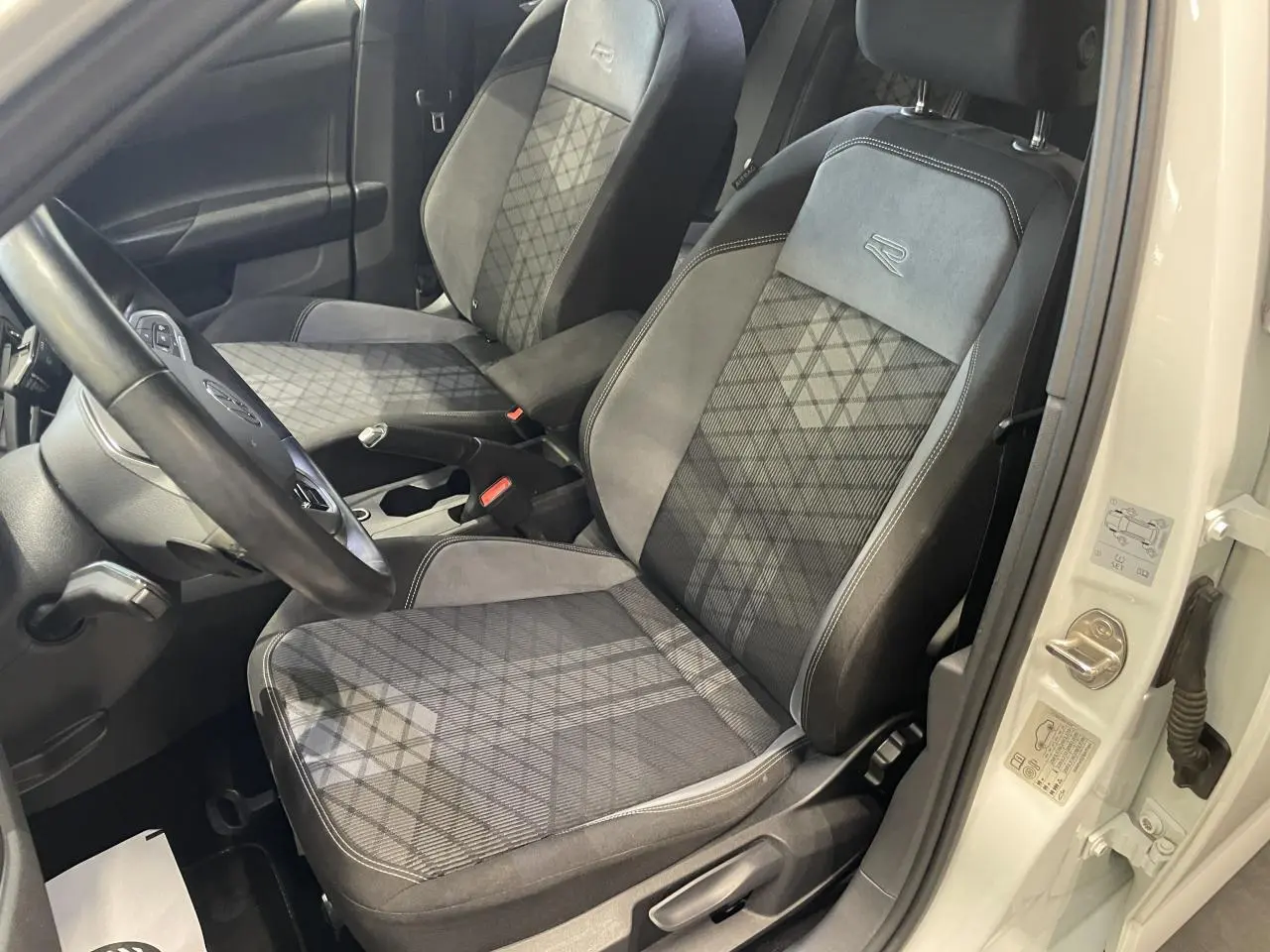 Vue intérieure côté conducteur de la Volkswagen Polo 1.0 TSI R-Line 2024 blanche, sièges tissu Karoso avec logo R brodé.