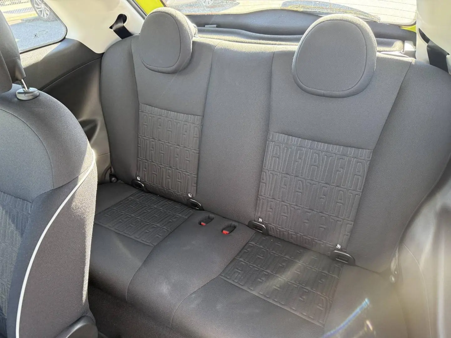 Vue intérieure de la banquette arrière noire avec motifs monogramme Fiat d'une FIAT 500 e jaune, côté droit visible.
