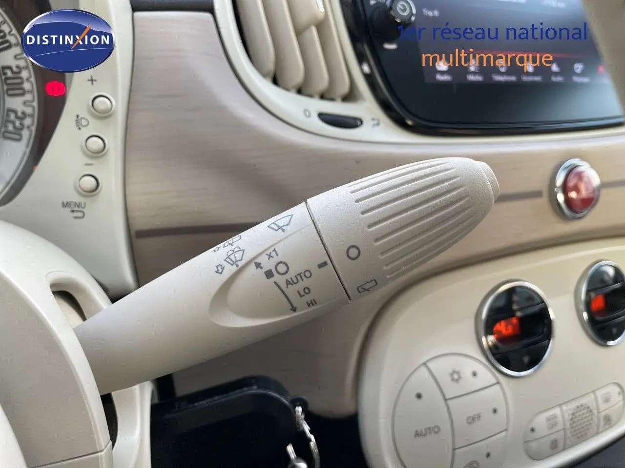 Gros plan sur la manette d'essuie-glace beige dans l'habitacle clair d'une Fiat 500 blanche, version DolceVita 2022.