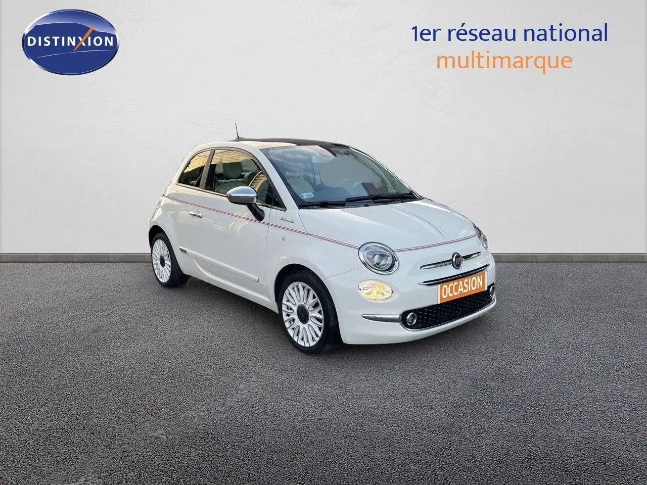 Fiat 500 1.0 Hybrid blanche vue 3/4 avant droit avec jantes blanches et phares allumés sur fond neutre.