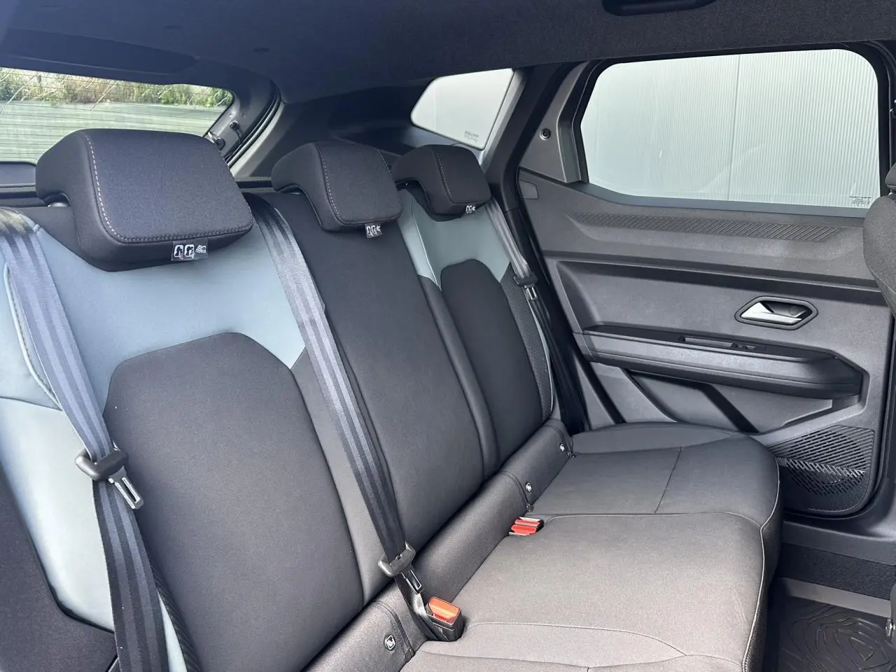 Vue intérieure côté droit des sièges arrière noirs du Dacia Duster 2025 Gris Schiste avec ceintures et appuie-têtes intégrés.