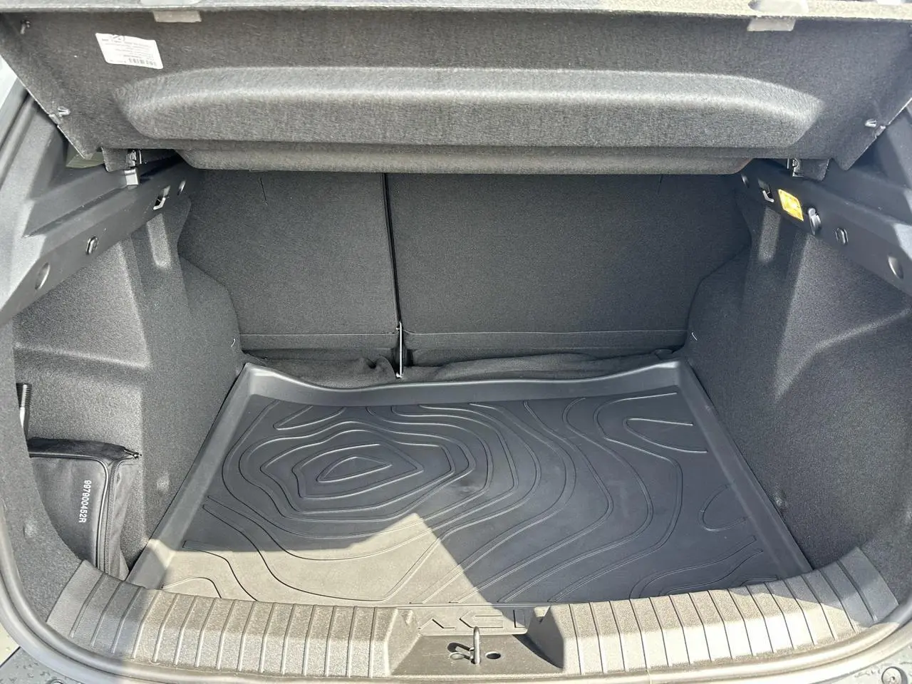 Coffre ouvert du Dacia Duster ECO-G 100 Extrême gris Schiste, montrant le tapis de sol caoutchouc texturé.