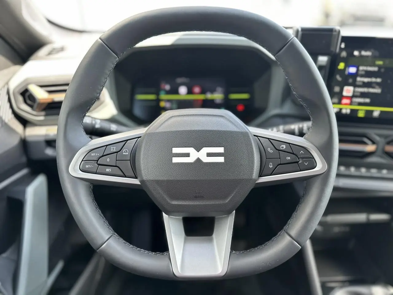 Volant cuir noir du Dacia Duster 2025 ECO-G 100 Extrême avec commandes intégrées et tableau de bord digital flou en arrière-plan.