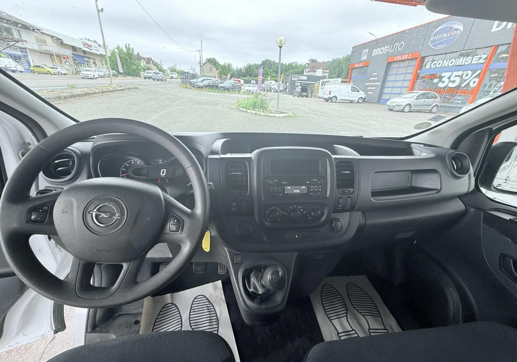 Vue intérieure avant de l'Opel Vivaro blanc 2018, montrant le volant, tableau de bord et levier de vitesse manuel.