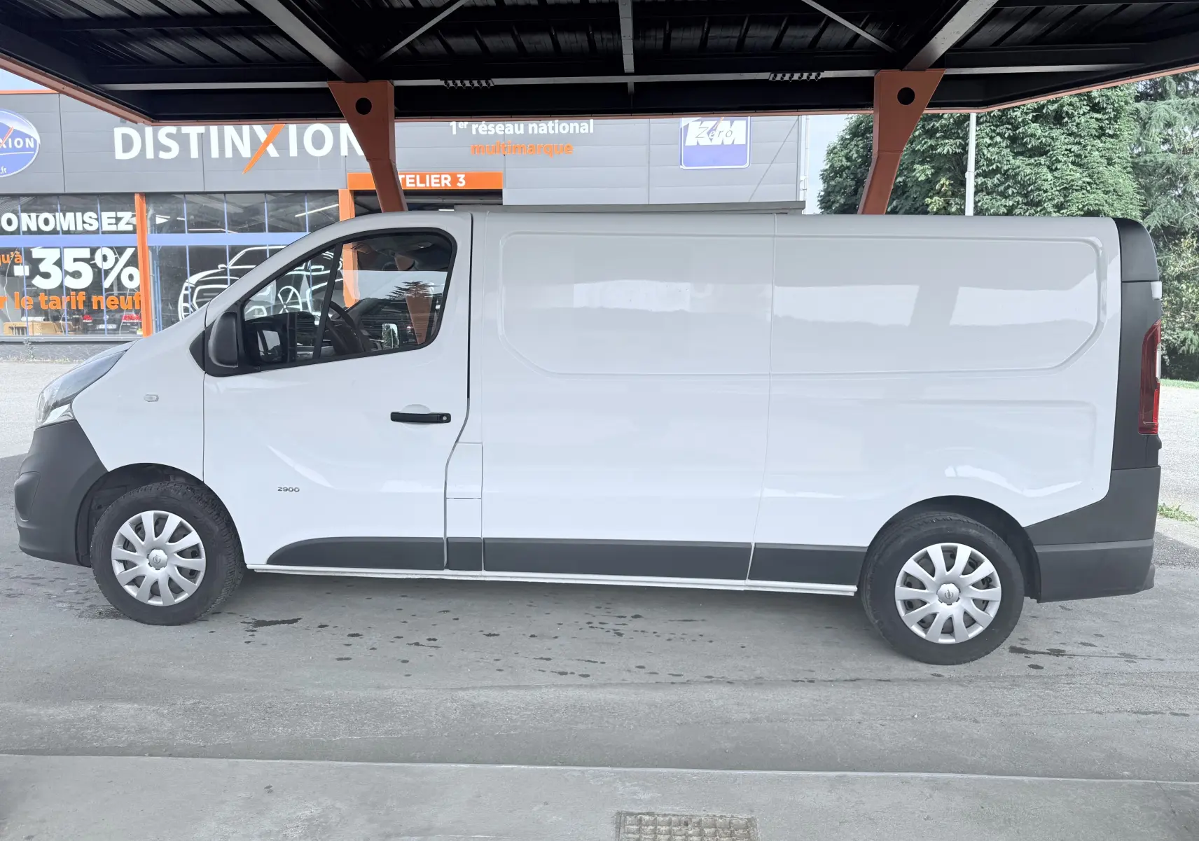 Vue de profil côté gauche d’un utilitaire Opel Vivaro blanc sous abri, avec jantes acier et enjoliveurs.