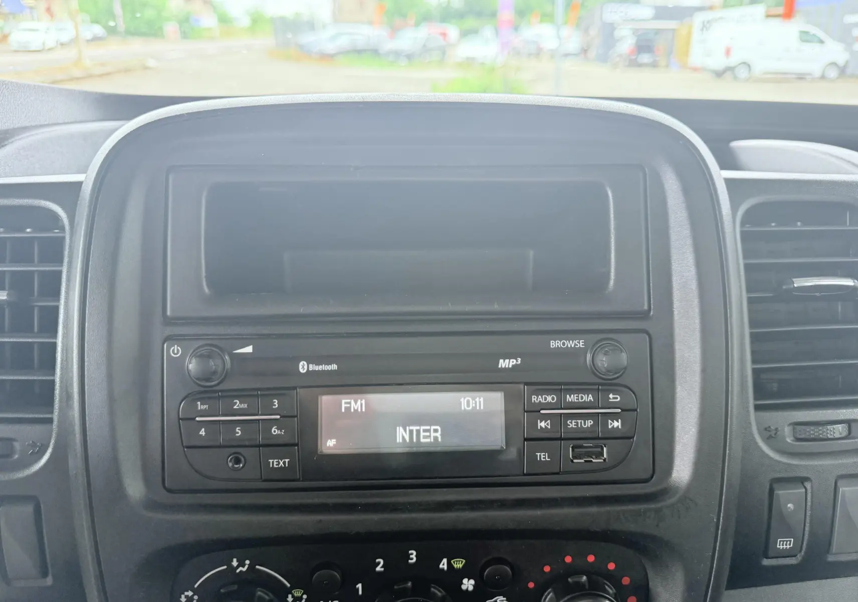 Vue rapprochée du tableau de bord noir de l’Opel Vivaro 2018, avec autoradio et commandes de climatisation visibles.