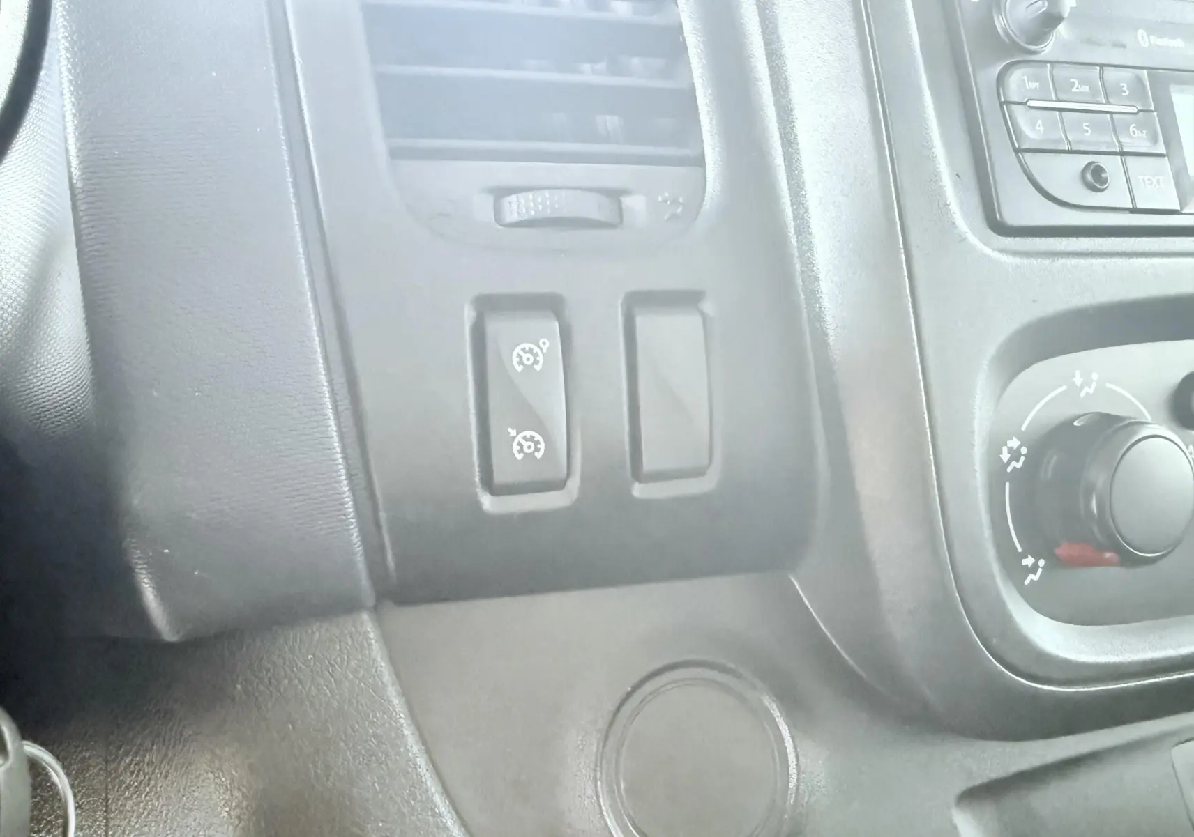 Détail du tableau de bord noir de l'Opel Vivaro 2018, avec commandes du régulateur de vitesse et ventilation.