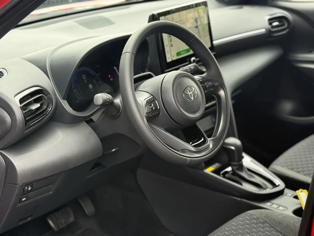 Vue intérieure côté conducteur du Toyota Yaris Cross 1.5 Hybrid 2026, volant cuir et écran tactile central visibles.