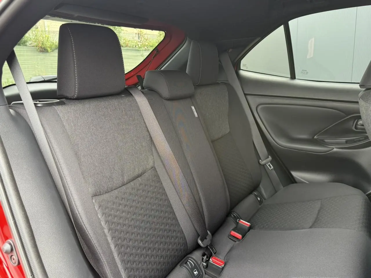 Vue intérieure des sièges arrière noirs de la Toyota Yaris Cross 1.5 Hybrid 2026, avec ceinture de sécurité visible côté gauche.