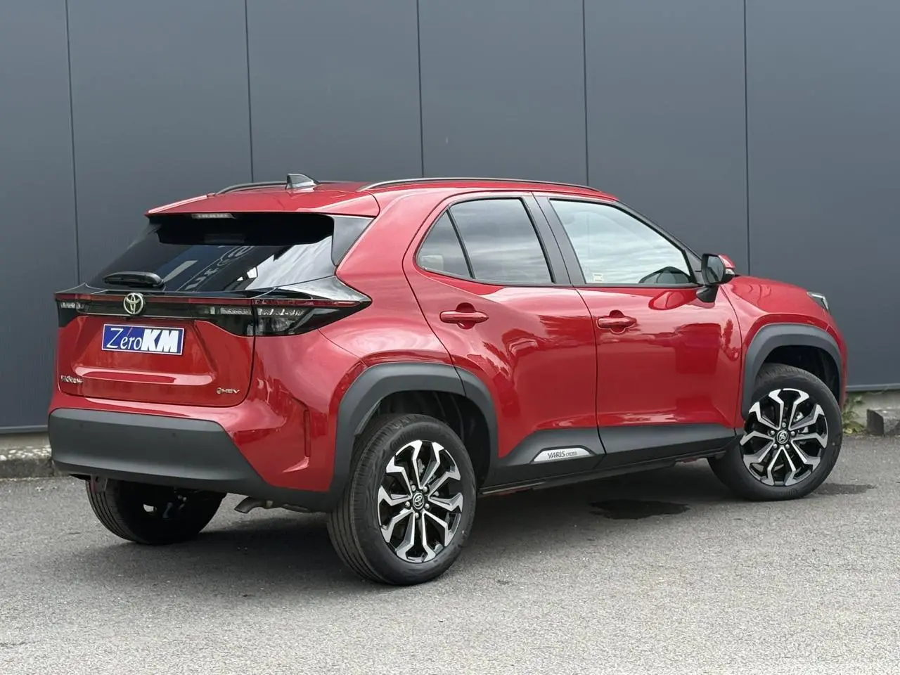 Vue 3/4 arrière droite d'une Toyota Yaris Cross rouge intense avec jantes alliage et détails noirs contrastants.