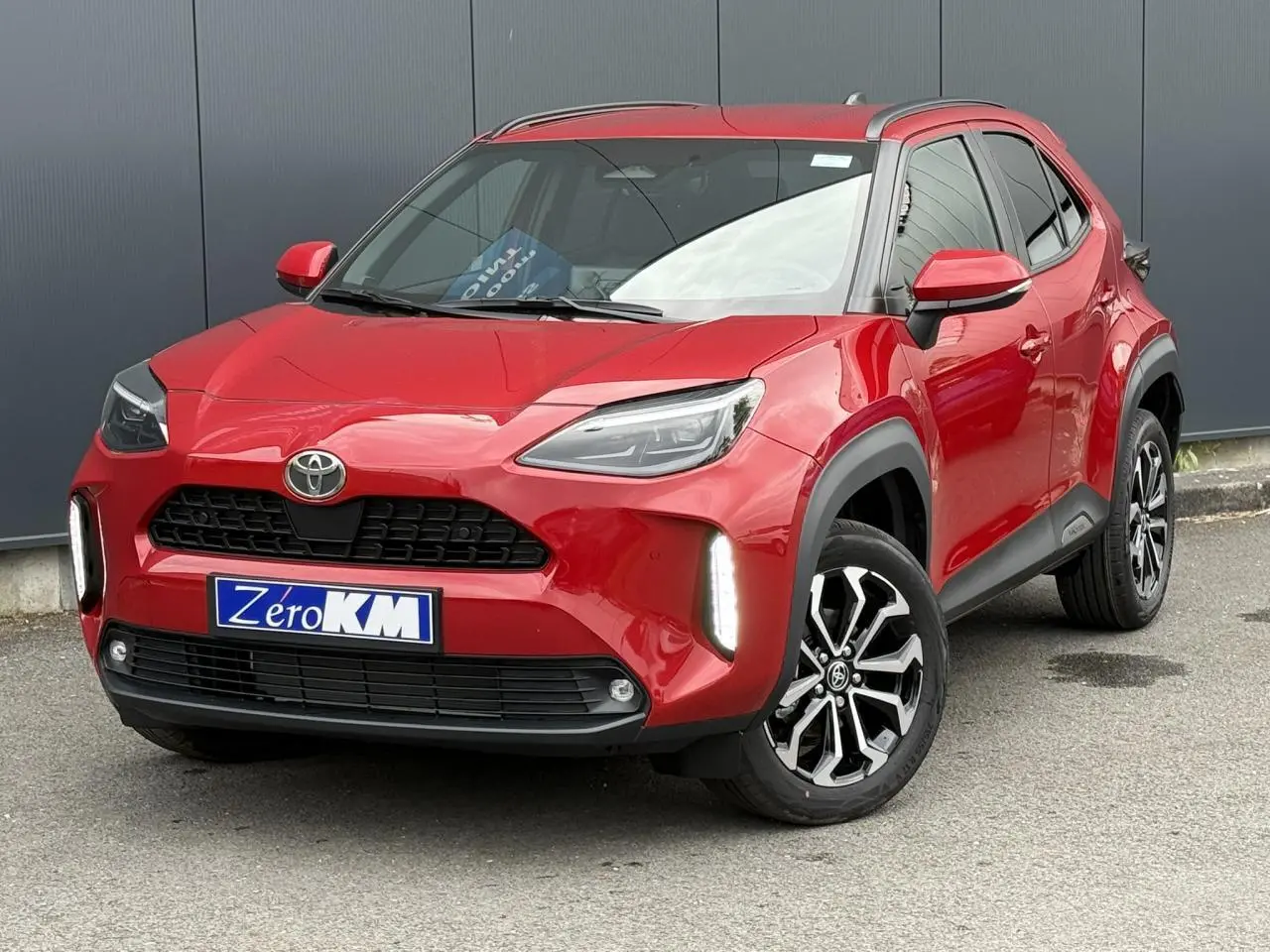 Toyota Yaris Cross rouge intense vue 3/4 avant droit avec feux LED et jantes alliage noires.