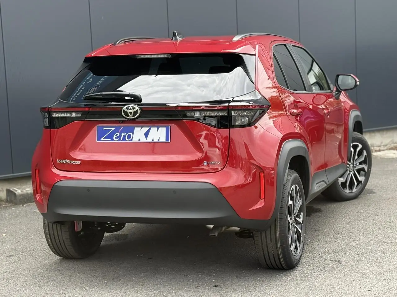 Vue 3/4 arrière droite d'une Toyota Yaris Cross rouge intense avec feux arrière LED et jantes alliage noires.
