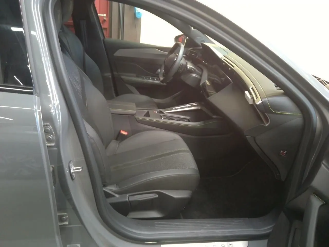 Vue intérieure côté conducteur de la Peugeot 408 Hybrid 145 GT gris selenium, avec sièges noirs et tableau de bord moderne.