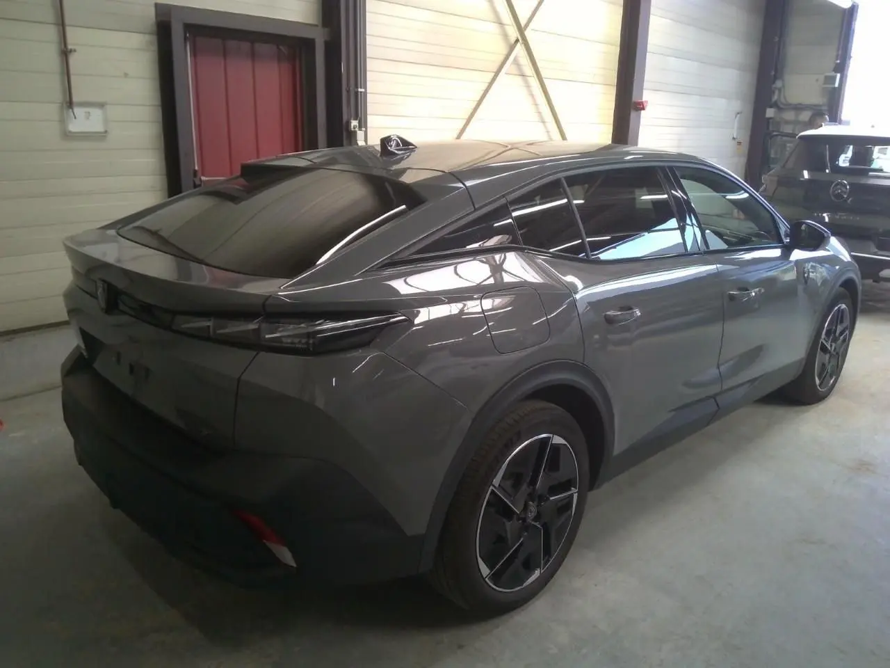 Peugeot 408 gris selenium vue de profil côté gauche, avec jantes noires et détails modernes sur la carrosserie.