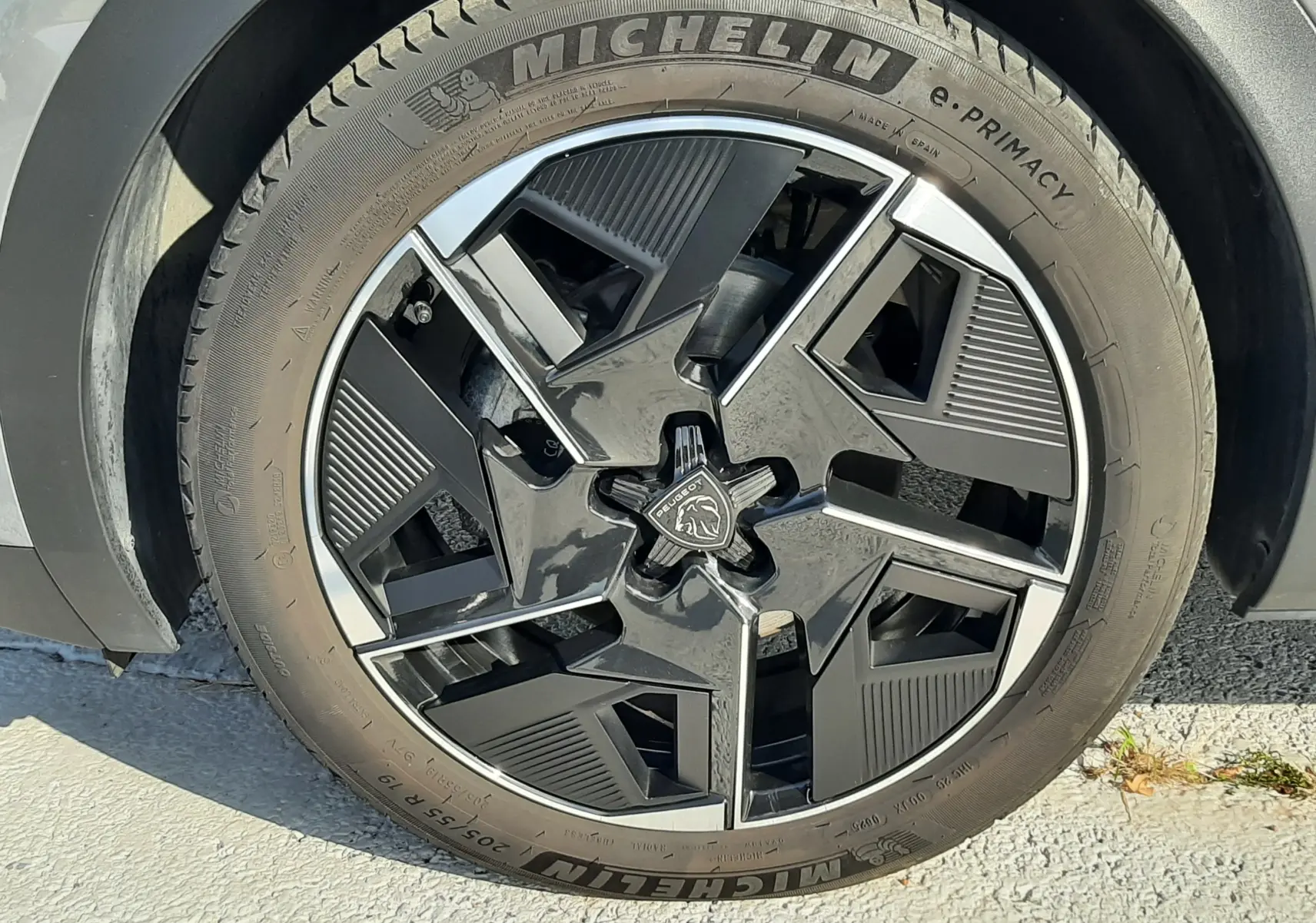 Gros plan sur la roue avant droite d’une Peugeot 408 gris selenium avec jante noire et argentée au design géométrique.
