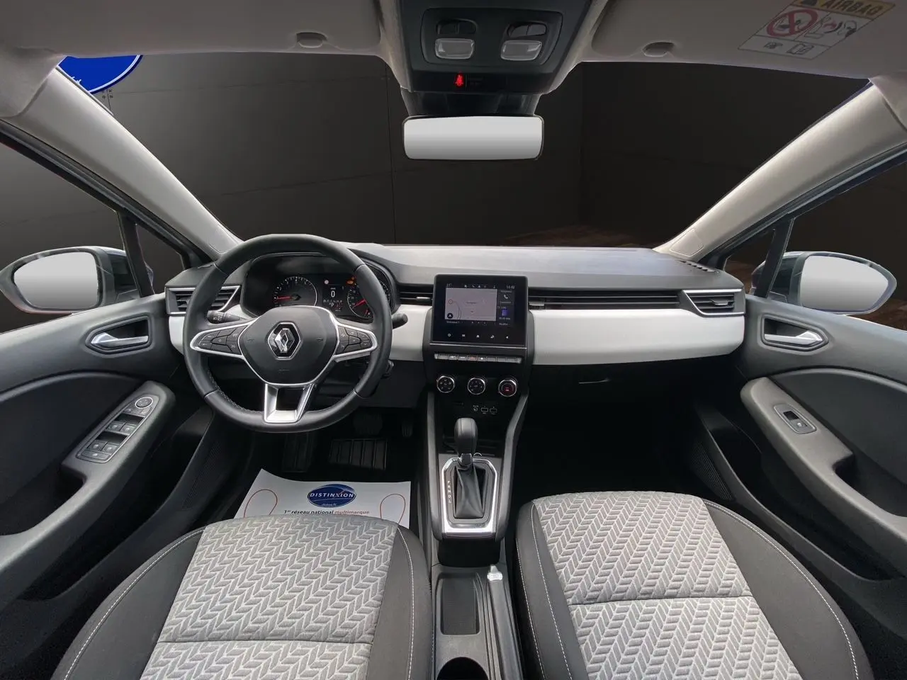 Intérieur de Renault Clio V TCE 90 gris Highland, vue frontale sur tableau de bord, volant multifonction et écran tactile central.