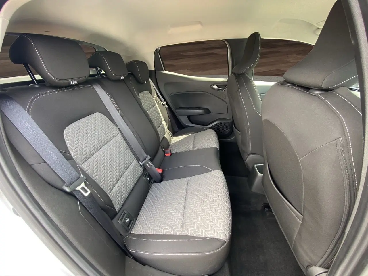 Vue intérieure arrière montrant les sièges arrière en tissu noir et gris de la Renault Clio V TCE 90 Evolution 2023.