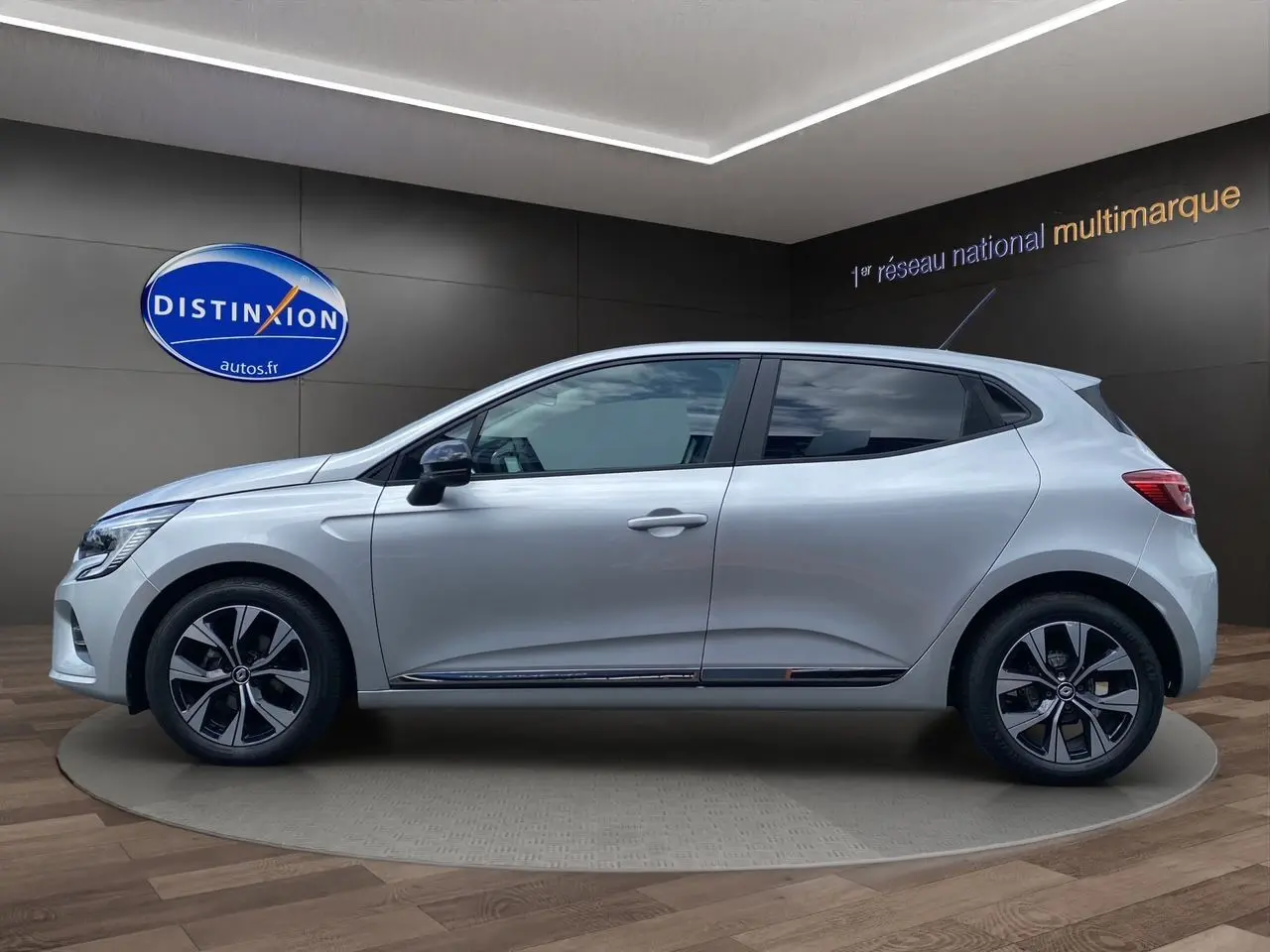 Profil droit d'une Renault Clio V gris Highland avec jantes alliage et vitres teintées en showroom.