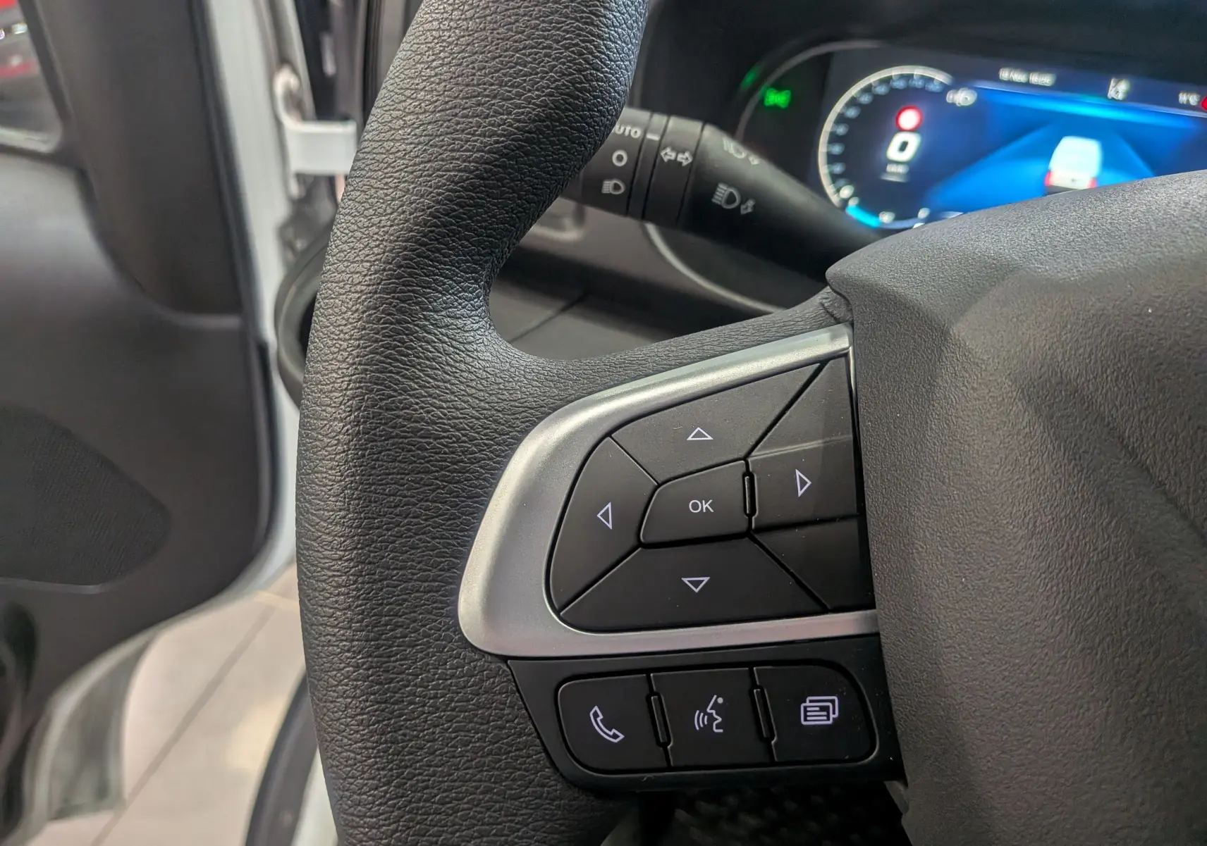 Gros plan sur les commandes au volant noir et argent du tableau de bord du fourgon Iveco Daily 2025 blanc.