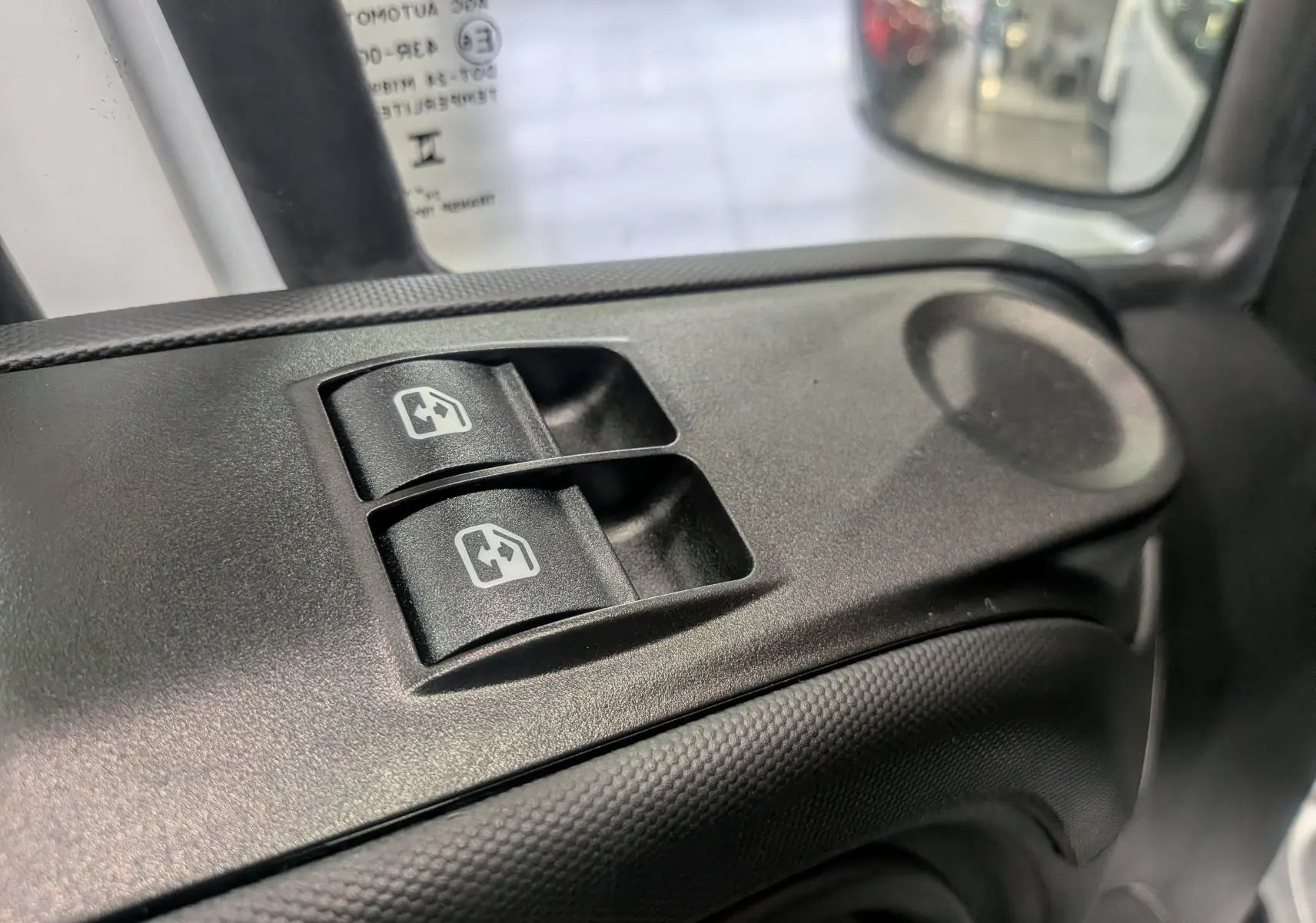 Boutons de commande des vitres électriques sur la portière côté gauche d'un Iveco Daily Fourgon blanc 2025.