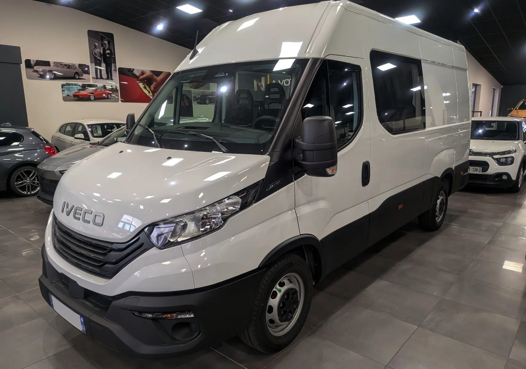 Fourgon blanc Iveco Daily 2025 vu en 3/4 avant droit, avec calandre noire et vitres latérales teintées.