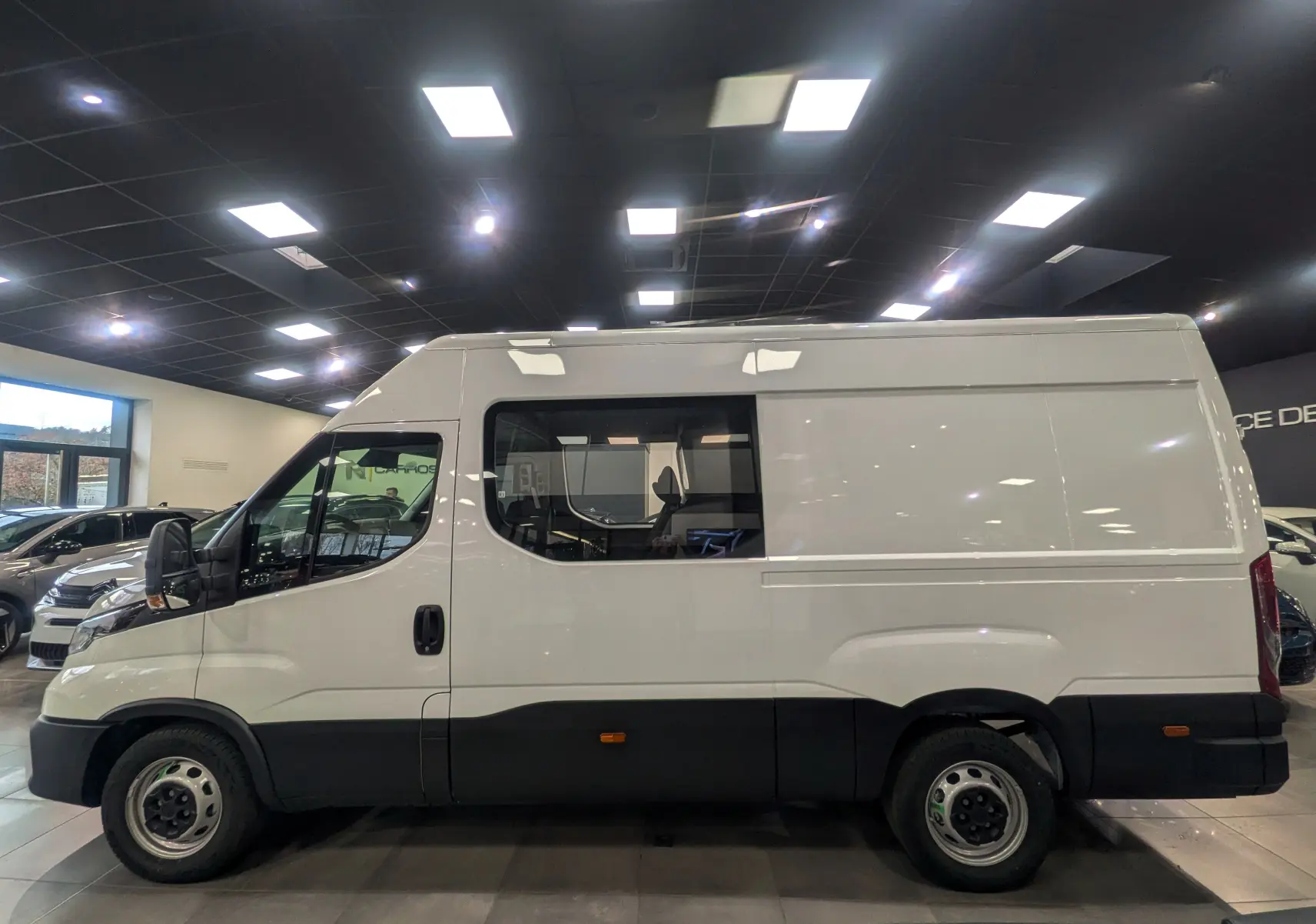 Vue de profil côté gauche d'un fourgon Iveco Daily blanc 2025 avec fenêtre latérale et carrosserie haute.