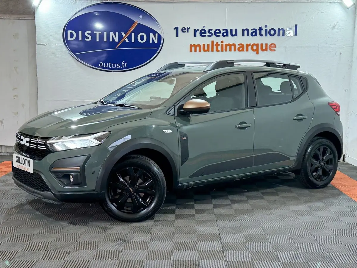 Vue 3/4 avant droite d'une Dacia Sandero Extreme+ TCe 110 2024 verte avec jantes noires et barres de toit assorties.