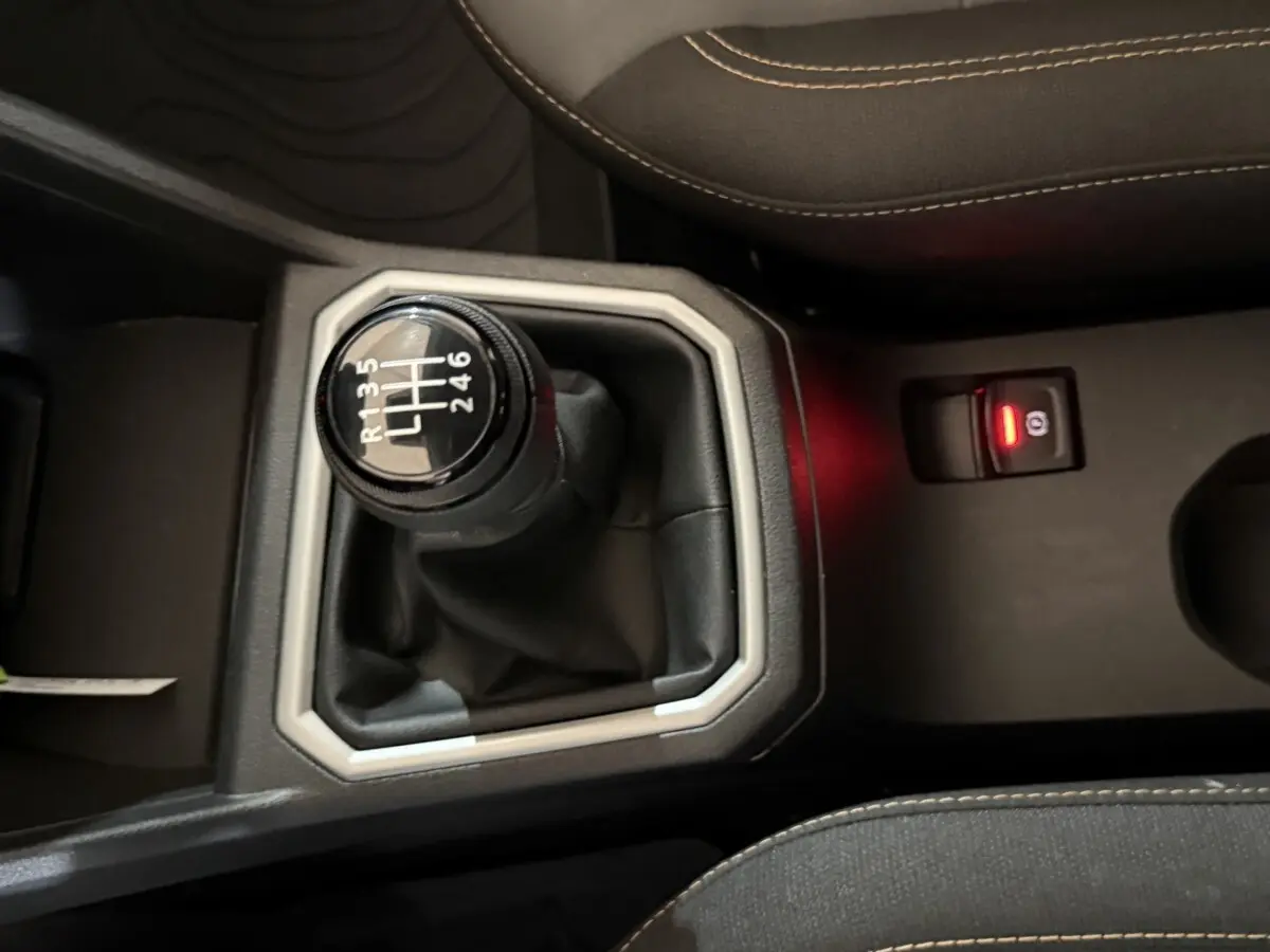 Gros plan sur le levier de vitesses manuel noir et gris de la Dacia Sandero Extreme+ TCe 110, avec coutures beige visibles.