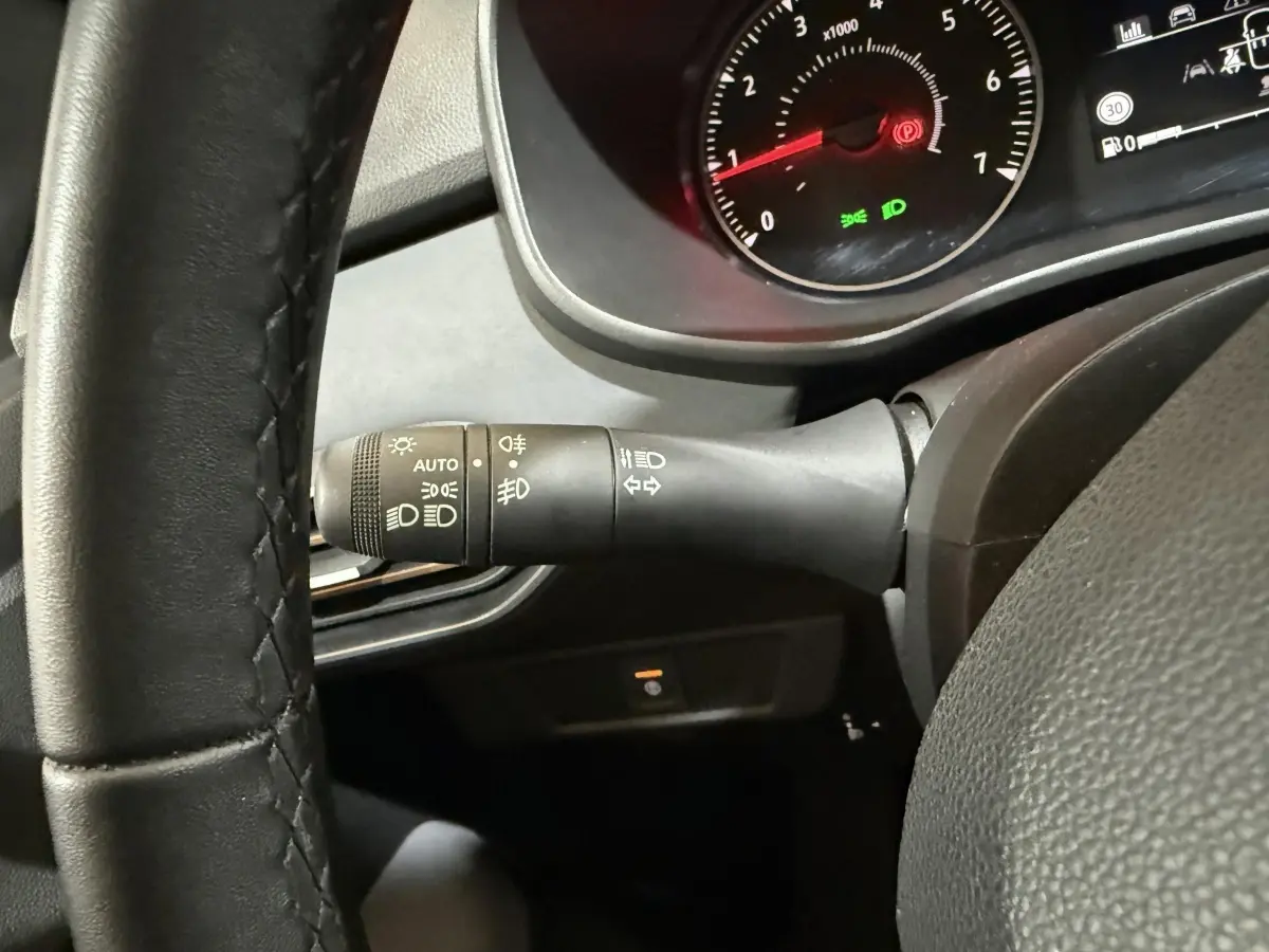 Gros plan sur la manette de phares à gauche du volant noir du tableau de bord du Dacia Sandero 2024.