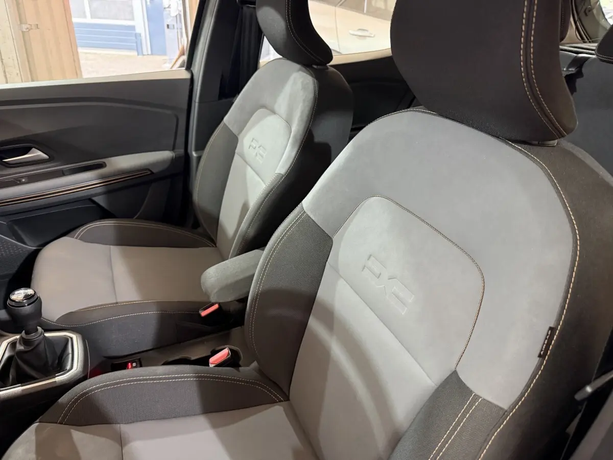 Vue intérieure rapprochée des sièges avant gris et noirs avec logo Extreme+ sur une Dacia Sandero 2024.