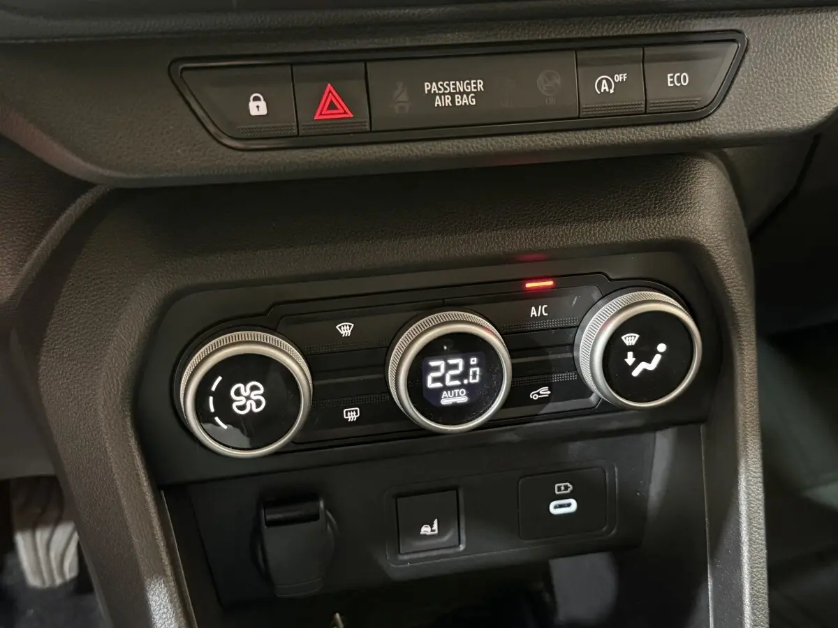 Gros plan sur la console centrale noire de la Dacia Sandero 2024, montrant les commandes de climatisation et boutons fonctionnels.