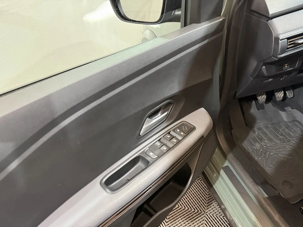Vue intérieure côté conducteur de la porte et seuil vert d'une Dacia Sandero Extreme+ TCe 110 2024 avec commandes de vitres.