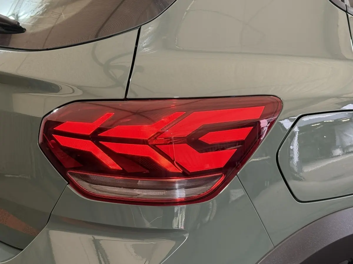 Gros plan sur le feu arrière droit rouge d’une Dacia Sandero Extreme+ TCe 110 vert 2024, avec la trappe à carburant visible.