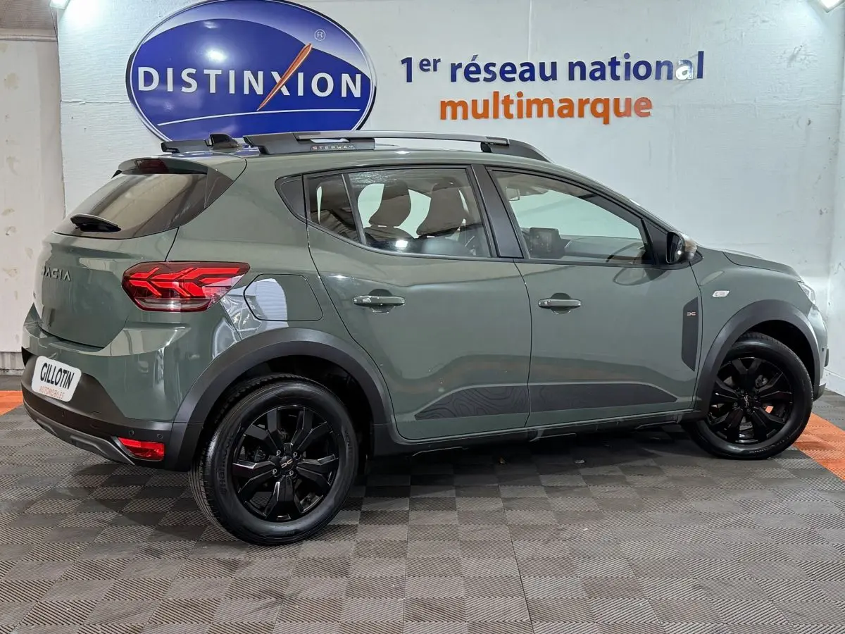 Vue de profil droit d'une Dacia Sandero Extreme+ TCe 110 2024 vert avec jantes noires et barres de toit assorties.