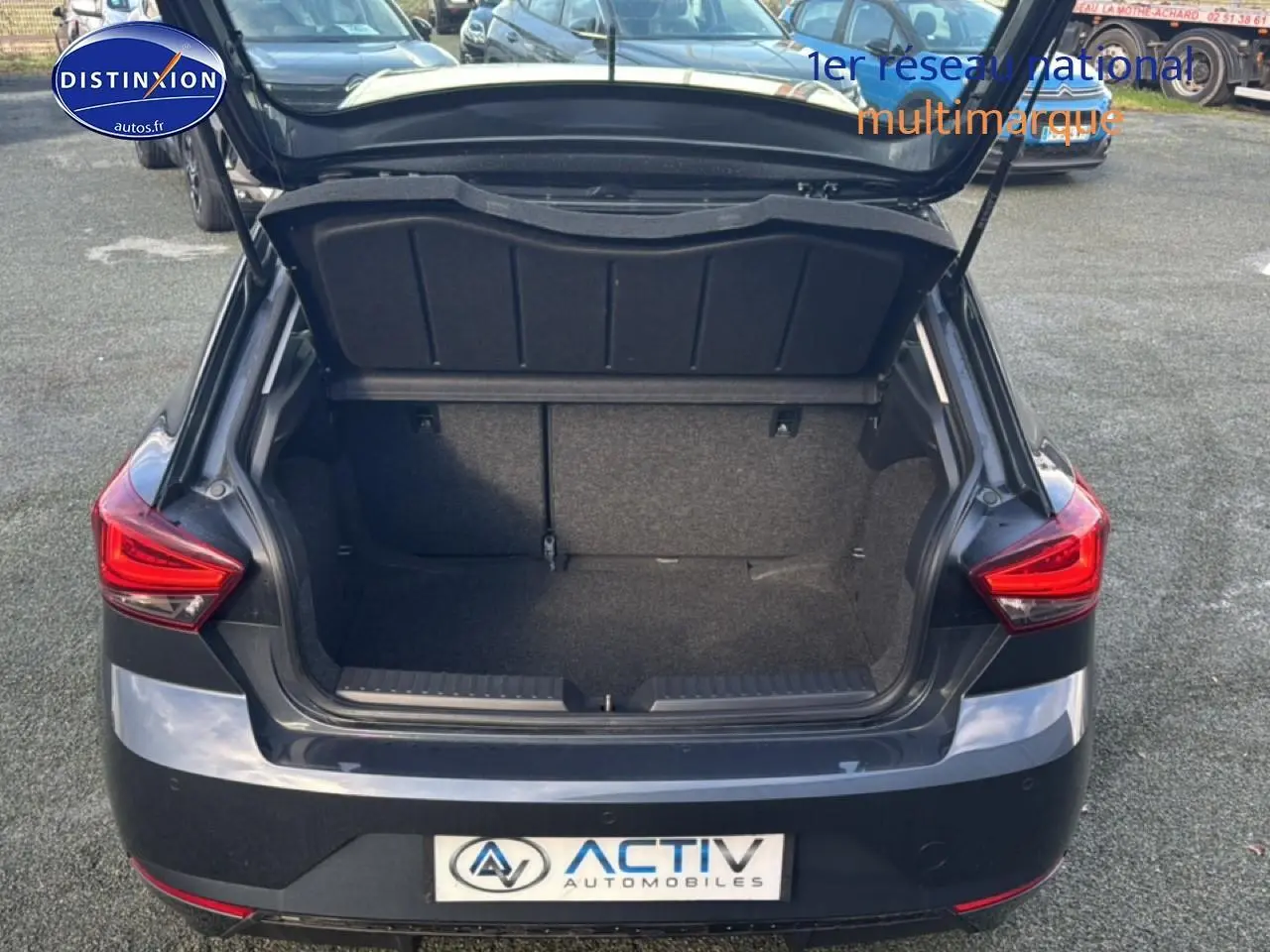 Vue arrière d'une SEAT Ibiza 1.0 TSI 95 Copa gris magnétique avec coffre ouvert montrant l'espace de chargement.