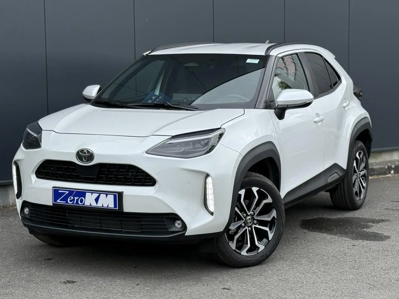 Toyota Yaris Cross blanc lunaire vue 3/4 avant droit avec phares LED et jantes alliage noires.