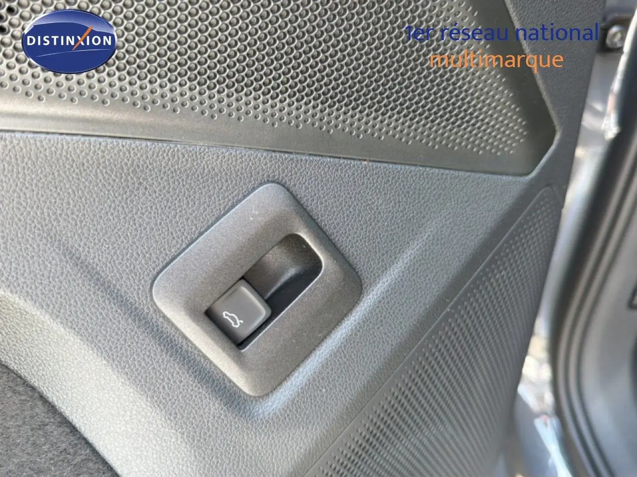Gros plan sur le bouton d'ouverture du coffre côté gauche d'un Volkswagen Tiguan gris dauphin métal 2026.