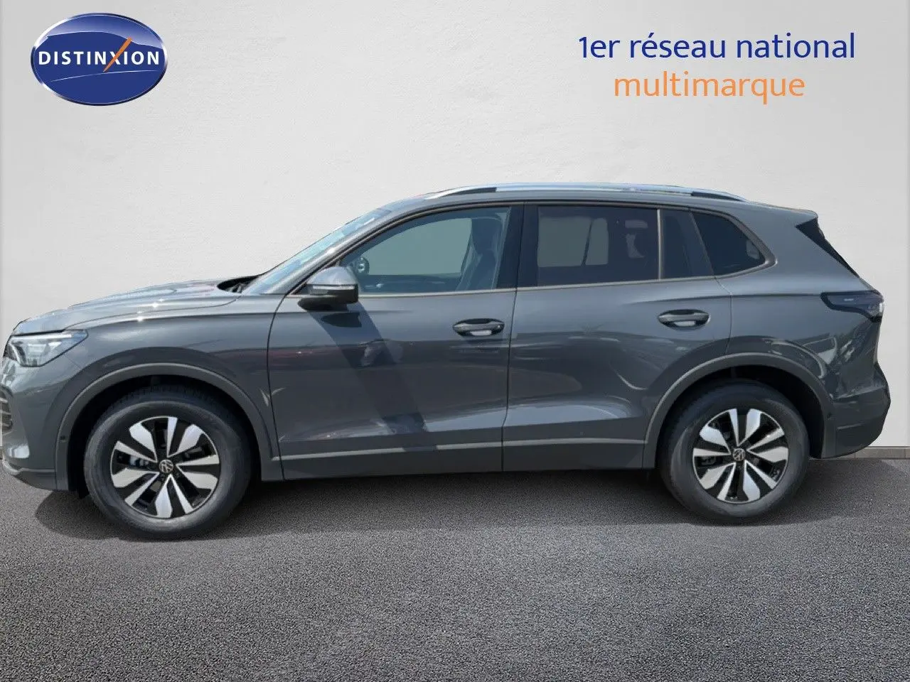 Vue de profil côté gauche d'un Volkswagen Tiguan gris dauphin métal, SUV compact avec jantes alliage bicolores.