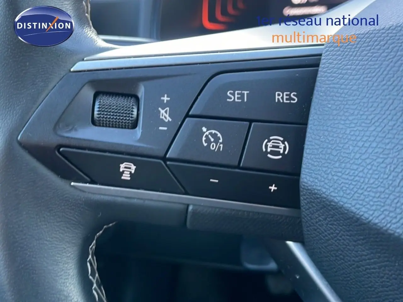 Gros plan sur les commandes de régulateur de vitesse au volant d’un SEAT Arona blanc toit gris, intérieur noir.