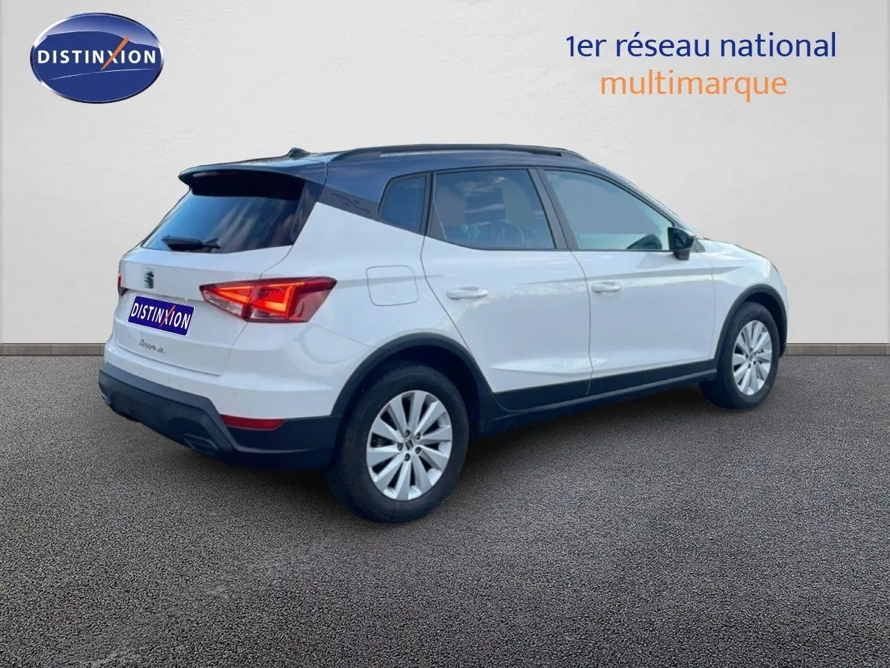 Vue 3/4 arrière droite d'un SEAT Arona blanc avec toit gris, mettant en valeur son design compact et moderne.