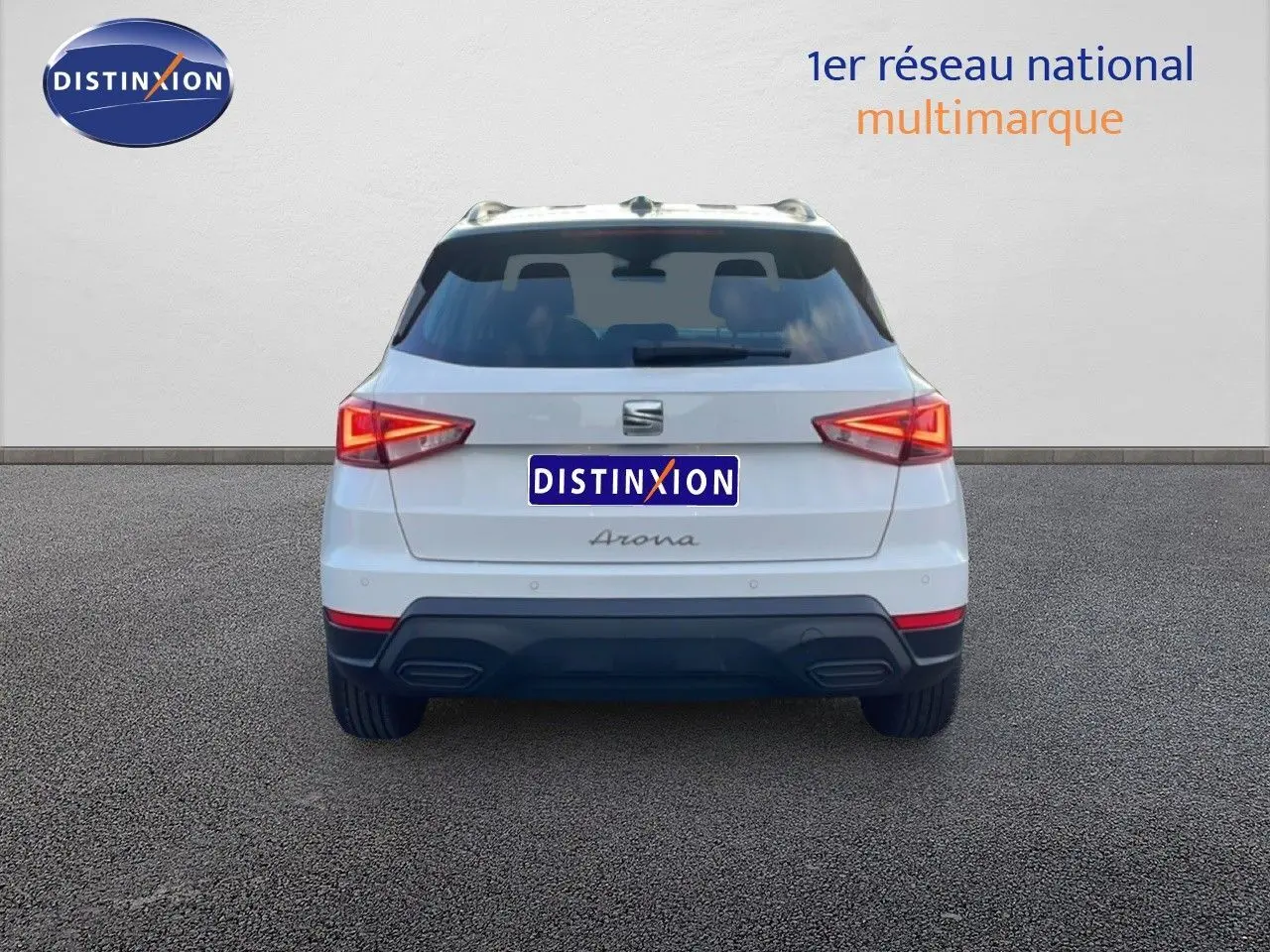 Vue arrière d'un SEAT Arona blanc avec toit gris, feux arrière allumés et double sortie d'échappement intégrée.