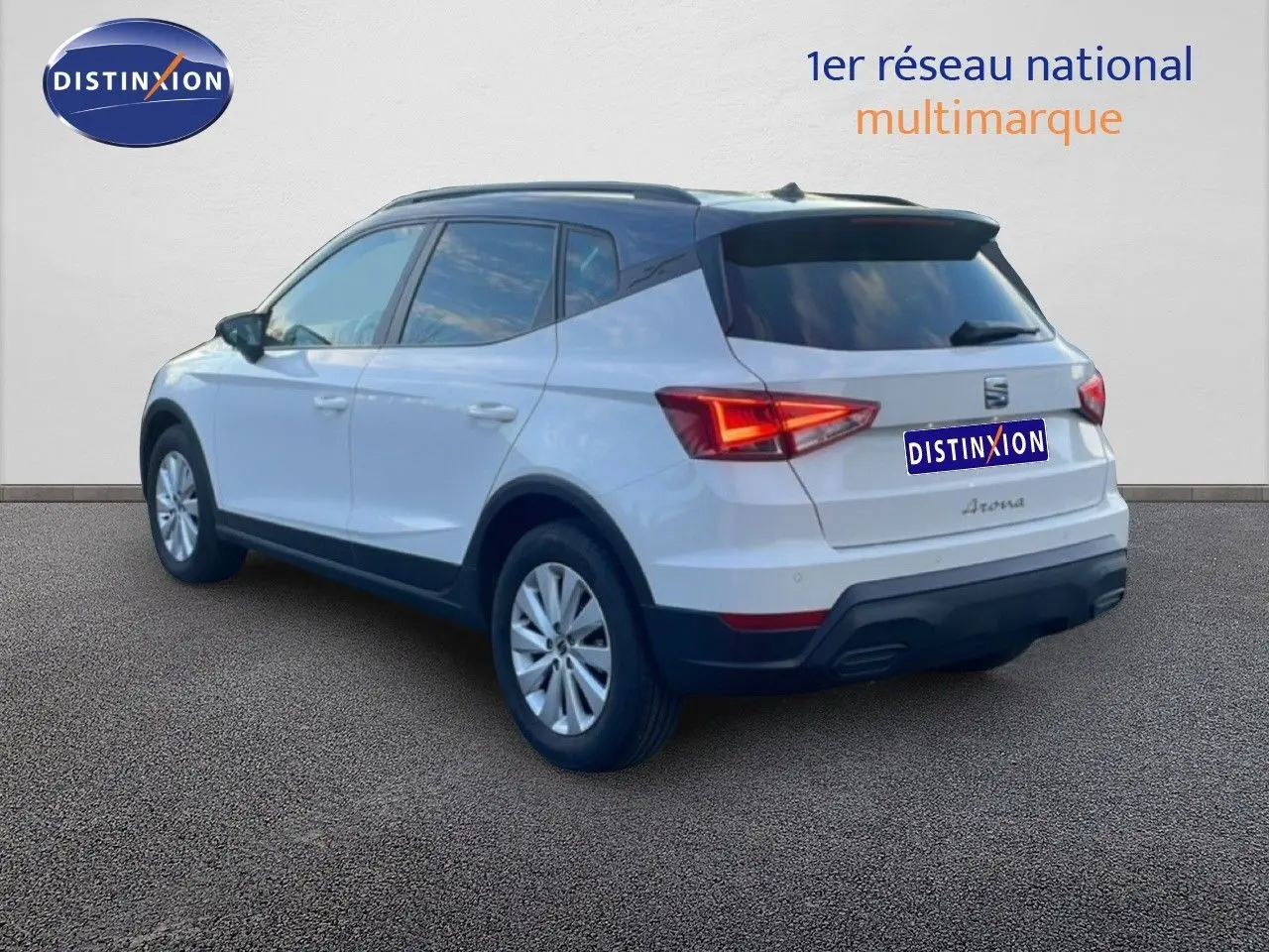 Vue 3/4 arrière droite d’un SEAT Arona blanc avec toit gris, feux arrière allumés et jantes argentées.