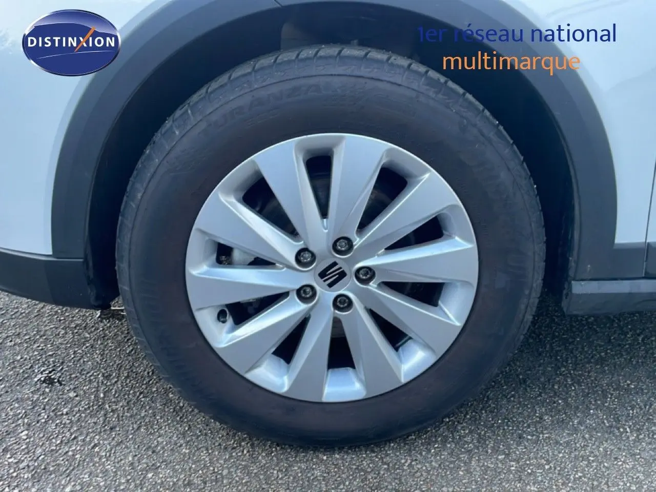 Gros plan sur la roue avant gauche blanche du SEAT Arona 2025 avec jante argentée et logo central visible.