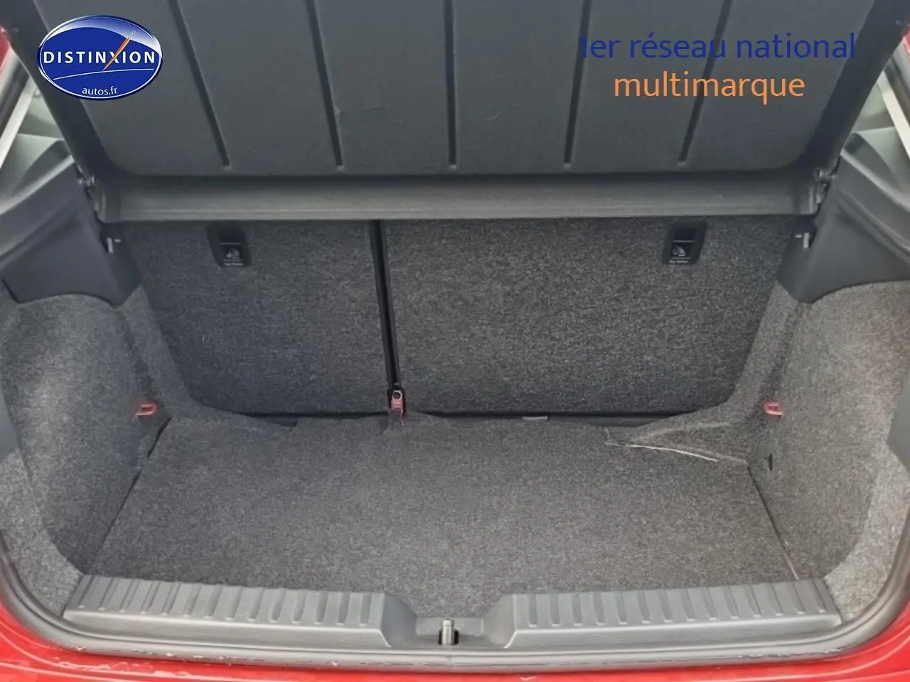 Coffre ouvert vu de l'arrière d'une SEAT Ibiza rouge désir avec banquette arrière rabattable visible.