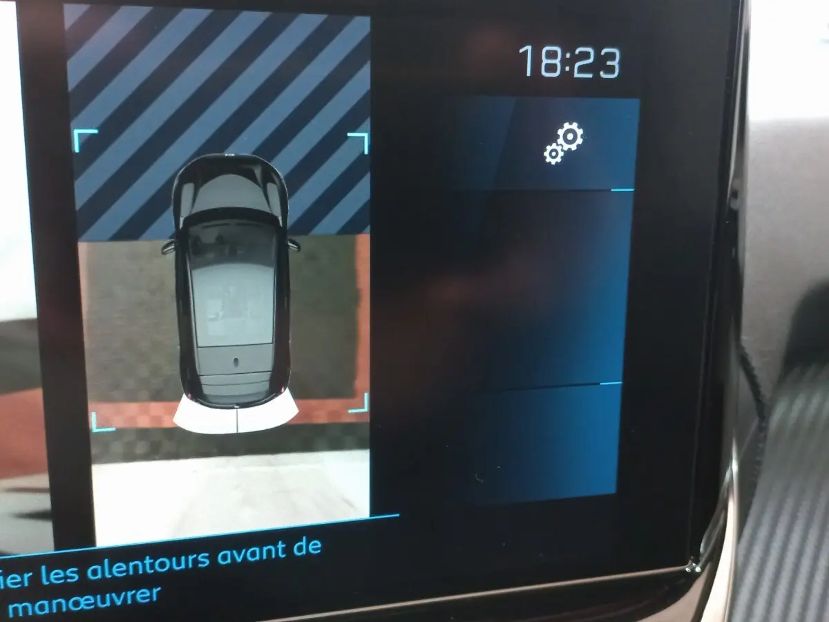 Affichage tactile intérieur montrant la vue aérienne en noir de la Peugeot 208 PureTech lors d'une manœuvre.
