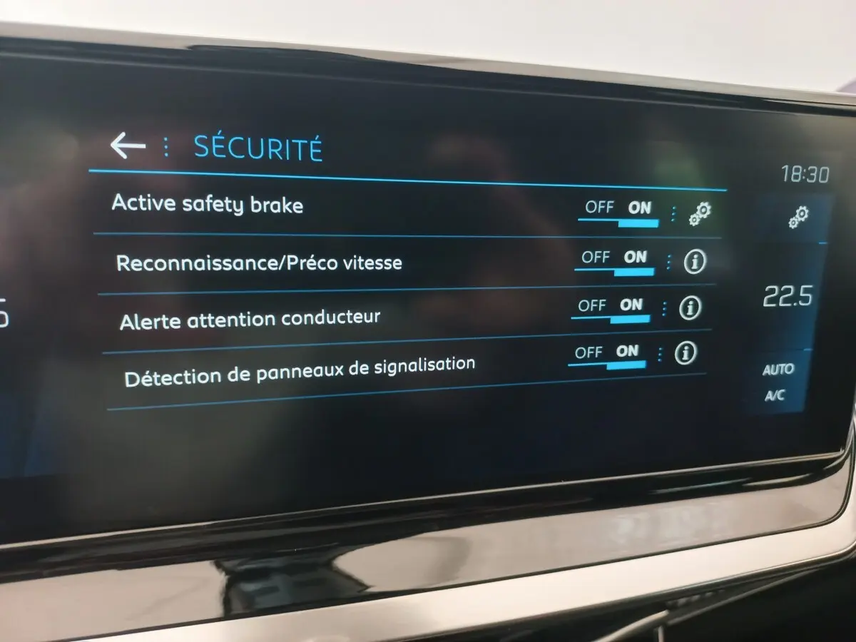 Écran tactile intérieur du tableau de bord de la Peugeot 208 PureTech 100 noir, affichant les options de sécurité activées.
