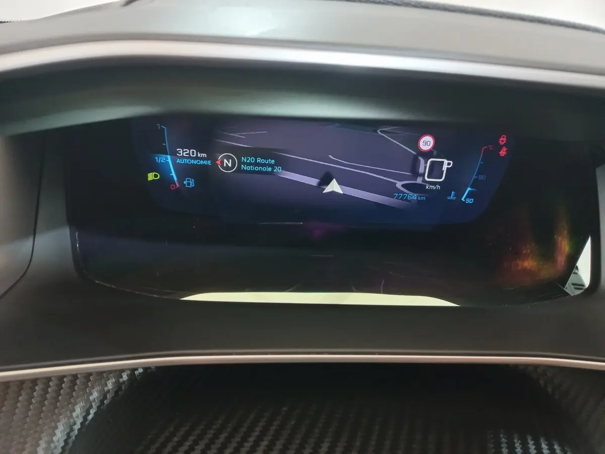 Affichage numérique du tableau de bord de la Peugeot 208 noir, montrant la navigation et les indicateurs de vitesse et autonomie.